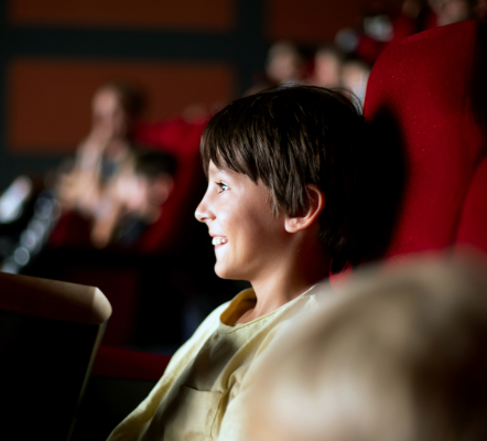 A small kid sitting in the audience smiling