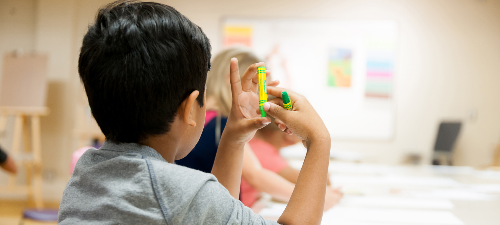 Little boy holding crayon in art class